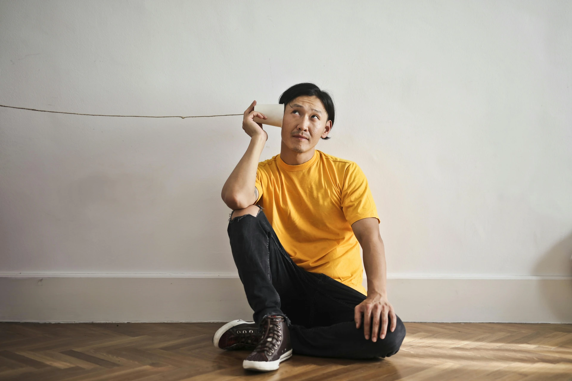 Man met bekers als telefoon aan oor